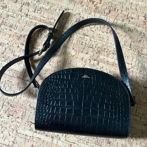 A.P.C. Demi-Lune bag in black leather embossed with a crocodile motif.